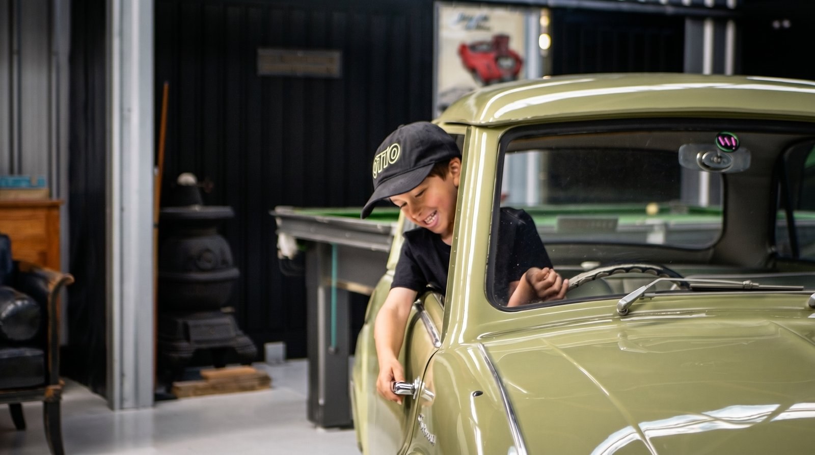 A young lad at the wheel of the little green car